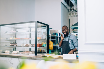 Canvas Print - Owner of small confectionery shop taking order by phone