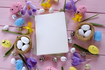 Easter Flat Lay.empty diary and easter decorative eggs in nests, spring flowers crocuses m daffodils on a pink wooden background.top view, copy space.Easter trendy background.Easter holiday