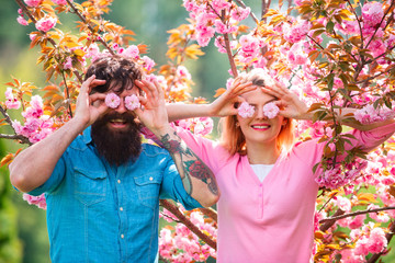 Best Valentines Day Ideas. Funny couple on Valentines Day. Romantic couple having a date in spring blooming park on a spring day with beautiful cherry blossoms in the background.