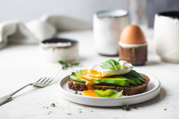 Healthy breakfast whole wheat toasted bread with avocado and poached egg over white background