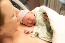 Mother Holding Newborn Baby Girl Moments After Birth. New Life, Giving Birth, Concept. 