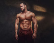 © Fxquadro - Portrait of attractive muscular bodybuilder at dark photo studio with blinks of light.
