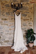 © IVASHstudio - Vintage wedding dress is Hanging on the lamp on the stone wall and plant