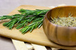 Bright fresh green and dried rosemary branches, twigs and leaves in a wooden bowl and board on light background.