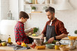 © deniskomarov - Father son cooking together by recipe in cookbook