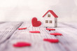 © Vitaliy - Toy house and red hearts on light defocused background. Valentines day concept