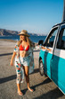 © ManuPadilla - Portrait of an attractive blonde smiling woman with straw hat getting in her camper van near the beach in summer - Close-up