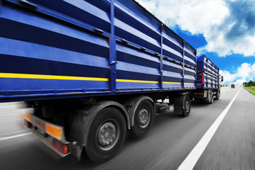 Wall Mural - Rear view of the big truck driving fast with trailer on the countryside road against blue sky