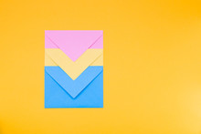 Three Envelopes Of Yellow, Blue And Pink Colors Nested In Each Other Lie On A Yellow Background Copy Space Top View, Minimalism Concept For Congratulations