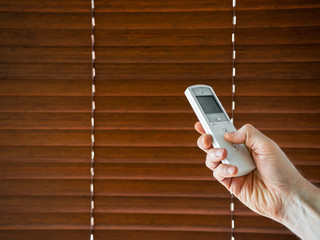 male hand holds a remote control to open the window blinds