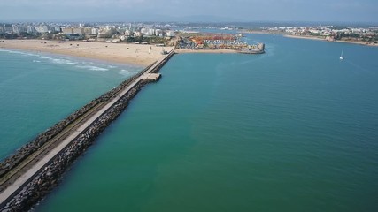 Canvas Print - Aerial. A pier and breakwaters at the entrance to the Arade River aerial view. Cities of Portimao. Praia de Rocha.