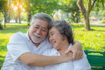 Wall Mural - Romantic senior couple. Elderly man or Senior asian husband embracing senior wife. Lovely elderly couple talking about their life, smiley faces at park. Old man and old woman love each other so much