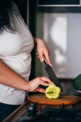 Overweight woman looking at recipe using his laptop and cooking in home kitchen. Culinary web blog, weight loss food