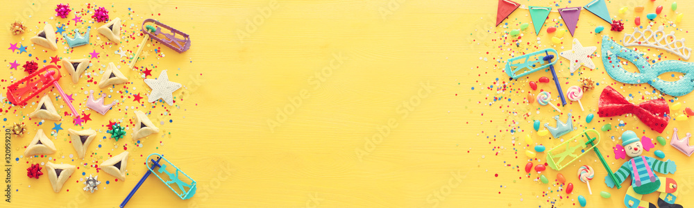 Purim celebration concept (jewish carnival holiday) over yellow wooden background. Top view, Flat lay - obrazy, fototapety, plakaty 