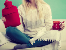 Woman Sitting On Couch Holding Hot Water Bottle