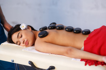 Woman lying on massage table with stones on her back at spa