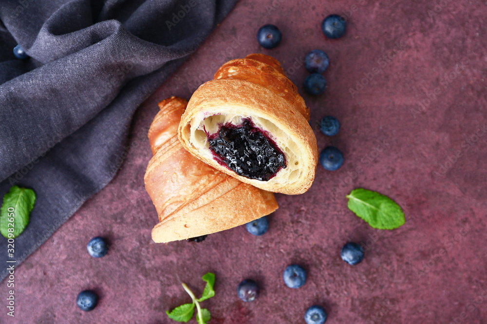 Tasty sweet croissant on color background