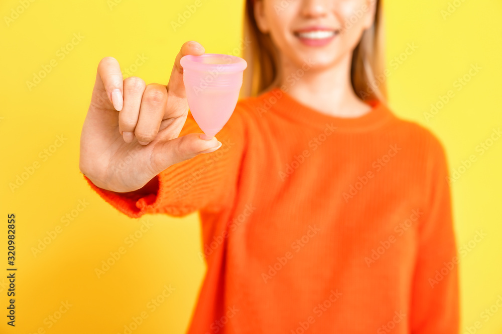 Young woman with menstrual cup on color background