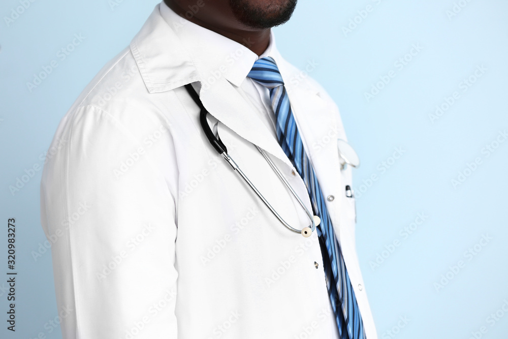 African-American doctor with stethoscope on color background
