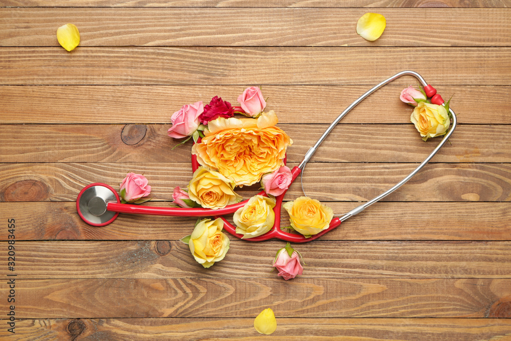 Stethoscope with flowers on wooden background