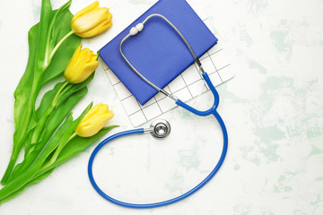 Stethoscope with flowers and notebooks on white background