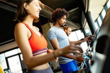 Wall Mural - Young people running on a treadmill in modern gym