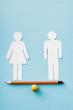 paper figures of couple as gender equality on pencil with ball isolated on blue, sexual equality concept
