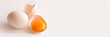 Broken egg and egg yolk on white panoramic background with copy space