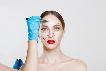 Facial cosmetic plastic surgery. Doctor surgeon hand in glove draw wrinkle lines on Woman face isolated white background. Sculpting reshaping Wrinkles fat removal cosmetic filling operation concept