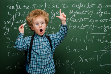 Wall Mural - curly kid in glasses gesturing near chalkboard with mathematical formulas