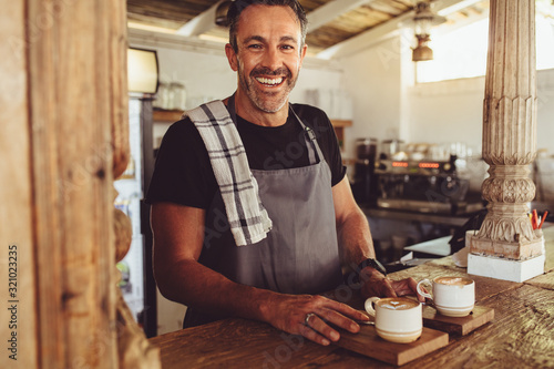 Cuadros en Lienzo Male barista serving coffee to customers