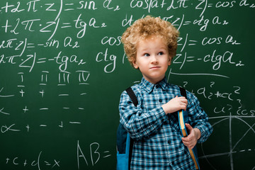 Wall Mural - smart kid standing with book near chalkboard with mathematical formulas