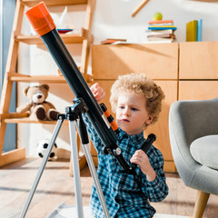 Wall Mural - smart child touching telescope near armchair
