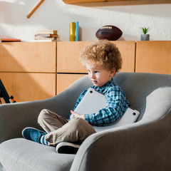 Wall Mural - smart kid sitting in armchair with laptop