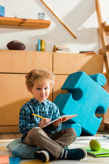 Wall Mural - smart kid writing in notebook while sitting on floor near apple and books