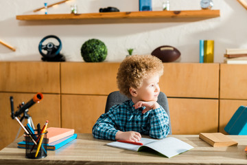 Wall Mural - smart child looking away near books on table