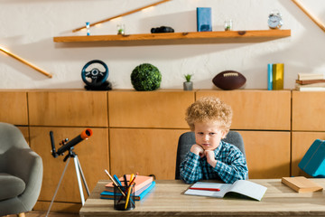 Wall Mural - upset kid sitting at desk with books