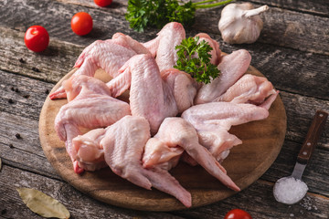 Canvas Print - Uncooked chicken wings  on a wooden cutting board with spices. Closeup