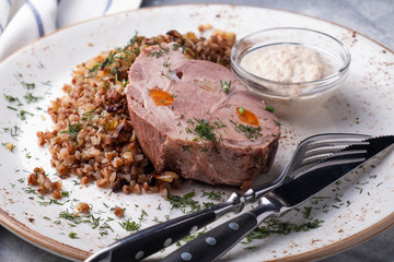 Wall Mural - Boiled pork with buckwheat cereal served with fork and knife. Closeup