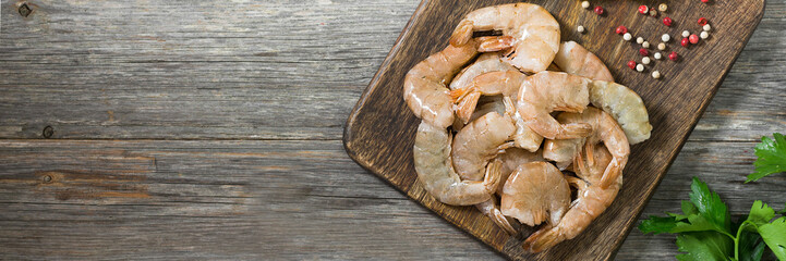 Tiger prawns on a wooden Board on a gray wooden table. Banner