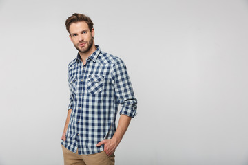 Wall Mural - Portrait of unshaven young man posing on camera with hands in pockets