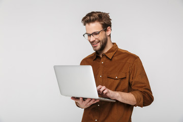 Wall Mural - Portrait of cheerful young man using laptop and smiling