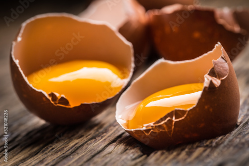 Fotomural Broken chicken eggs with yolk on wooden table