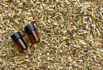 Background made of dried roots, flowers, herbs for medical use. Two dark bottles of essential oils on medical herb background with copy space. Phytotherapy backdrop. 