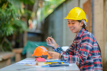 Asian woman architect   with yellow safety working on table at construction site