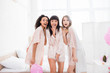 shocked multicultural girls in nightwear in bedroom with pink balloons