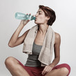© alex.pin - bella ragazza sportiva con il caschetto beve acqua dalla bottiglia dopo aver fatto sport, isolata su sfondo bianco