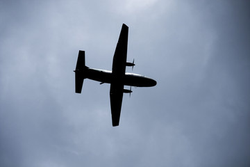 Silhouette two engine propeller airplane on sky, photoshoot from under while plane flying.