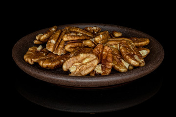 Wall Mural - Lot of whole tasty brown pecan half with brown ceramic coaster isolated on black glass