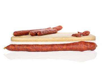 Wall Mural - Group of two whole one half lot of slices of piquant smoked sausage on bamboo cutting board isolated on white background